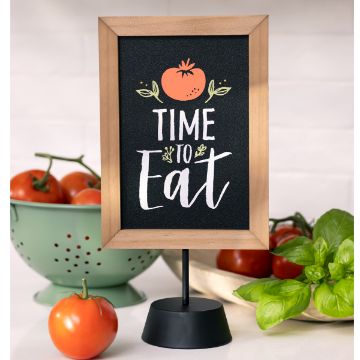 Show details for Kitchen Collection—Time to Eat A small framed chalkboard sign displays "Time to Eat" with a tomato illustration above the text. The sign is set on a stand. In the background, there are fresh tomatoes in and around a blue colander, and a bunch of fresh basil leaves, all created using the "transfer" from Chalk Couture.