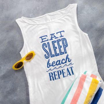 Show details for Eat, Sleep, Beach, Repeat A white Chalk Couture transfer with the words "Eat Sleep Beach Repeat" in blue, laid out on a gray surface. Next to it are yellow sunglasses and a folded towel with colorful stripes in pink, green, and yellow.