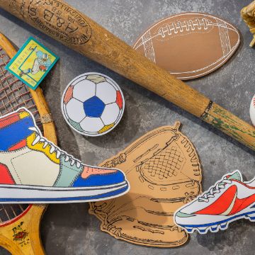 Show details for Varsity A flat lay photo featuring various sports items: a wooden baseball bat, a classic football, a vintage tennis racket, a baseball glove, a colorful high-top sneaker, a soccer ball, and Chalk Couture's transfer pair of sporty shoes, all arranged on a gray concrete surface.