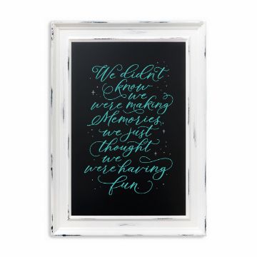 Show details for Couture Teal Paste Single A framed black sign with white distressed edges displays a decorative cursive quote in light blue: "We didn't know we were making memories, we just thought we were having fun." Motion lines and stars accentuate the playful, handwritten style using Chalk Couture paste.