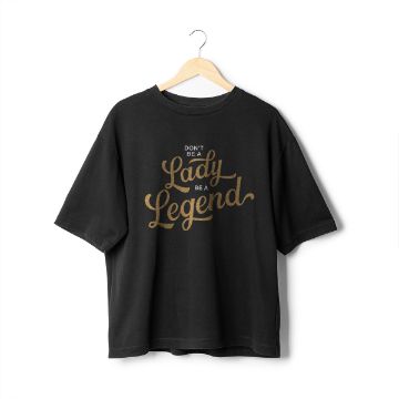 Show details for Shimmer Gold Ink Single A black T-shirt with the phrase "Don't Be A Lady, Be A Legend" written in stylish cursive text in gold using Chalk Couture ink. The shirt is displayed on a wooden hanger against a plain white background.