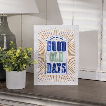 Show details for Reusable Medium Archway Shape  A decorative sign stands on a wooden surface next to a small potted plant. The sign features the text "These are the Good Old Days" with each word in a different color and font style. Sun rays graphic elements surround the text, adding a vintage feel.