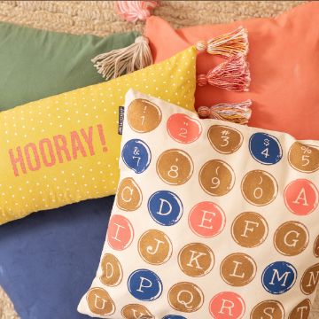 Show details for Antique Typewriter Keys Four colorful pillows are arranged together. One pillow has a yellow background with white polka dots and the text "HOORAY!" in pink, designed using the transfer from Chalk Couture. Another pillow features a playful coin and letter design. The other pillows are plain, one green and one orange with tassels.