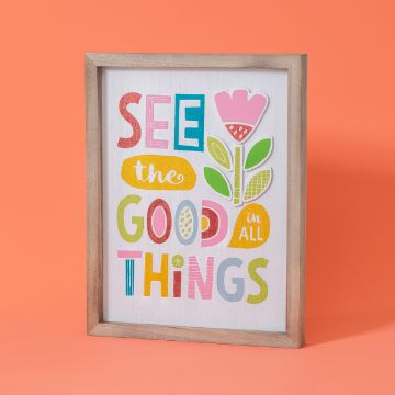 Show details for See The Good A framed sign with a wooden border features the colorful text "SEE the GOOD in ALL THINGS" alongside illustrations of a flower and leaves, set against a white background. The frame is placed in front of a solid orange backdrop, showcasing the transfer from Chalk Couture.