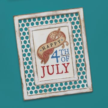 Show details for Happy 4th Of July Banner A framed decoration on a teal background reads "Happy 4th of July" with a patriotic design featuring a red, white, and blue banner. The frame has a rustic white finish with a honeycomb pattern around the edges. This artwork was created using the "Happy 4th of July" transfer from Chalk Couture.