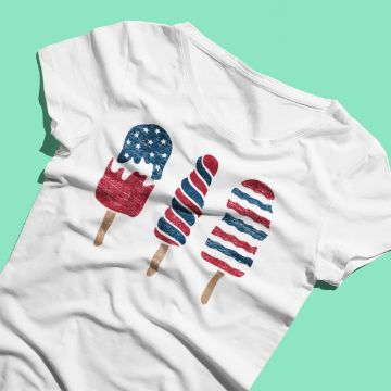 Show details for Popsicles A white t-shirt featuring three popsicles in red, white, and blue patriotic designs. The background is a solid sea-green color. The Chalk Couture transfer is decorated with stars and stripes in various patterns.