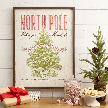 Show details for North Pole Country Store A holiday-themed print with "North Pole Village Market" written on it, featuring a decorated Christmas tree and text promoting baking supplies, holiday decor, gifts, and more. Nearby are wrapped presents, a jar of peppermint candies, cookies, and a small Christmas tree.
