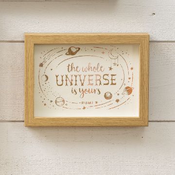 Show details for The Universe A wooden-framed sign displays the quote, "The whole universe is yours - Rumi," in artistic script surrounded by illustrations of planets and stars on a light background.