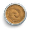 Top view of a round, open jar filled with smooth, light brown cream or paste. The product has a creamy texture, swirled in a slightly circular pattern, enclosed by a silver rim of the jar.