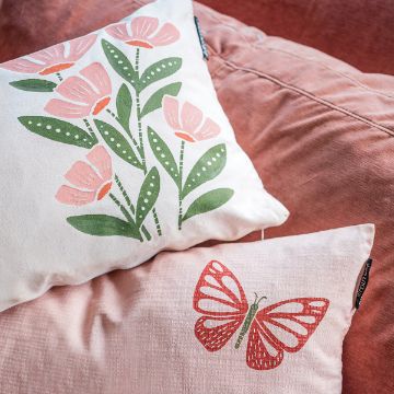 Show details for Spring Vibes Two decorative pillows on a textured, reddish-brown couch. The top pillow features a design of pink flowers with green leaves. The bottom pillow displays a red butterfly with intricate patterns on its wings.