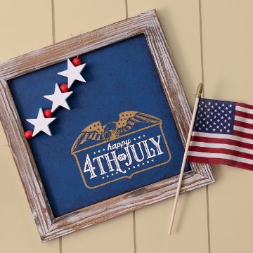 Show details for Happy 4th Of July Framed artwork with three white stars on a blue background, featuring a gold eagle above "Happy 4th of July" text. An American flag leans against the frame.