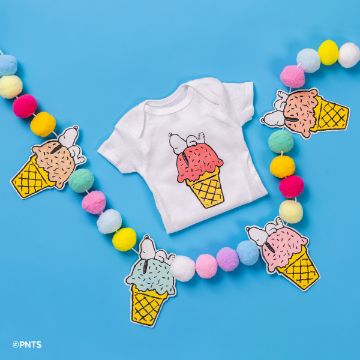 Show details for Peanuts - Ice Cream Cone Baby onesie with an ice cream cone design on a blue background, surrounded by colorful felt balls. Ice cream-shaped cutouts are placed around the onesie.