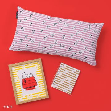 Show details for Peanuts - Snoopy Stripe Pattern A pink and white striped pillow with cartoon dog prints, a spiral-bound notebook with similar stripe design, and a framed picture of a cartoon dog and bird on a red doghouse, all arranged on a red surface.