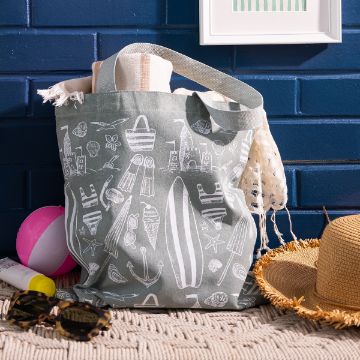 Show details for Beach Essentials A beach bag with white summer-themed illustrations sits on a woven mat, filled with a striped towel and net bag. Nearby are sunglasses, sunscreen, a sunhat, and a pink-and-white beach ball against a blue brick wall.