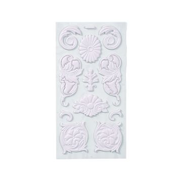 Show details for Damasque Artisan Add-Ons A sheet of decorative, raised white resin appliques with floral and scroll patterns arranged in a symmetrical design on a clear backing.