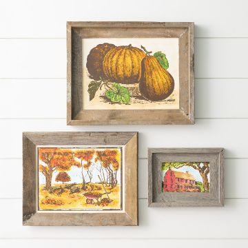 Show details for Autumn Days Three rustic wooden picture frames hang on a white shiplap wall. The art depicts pumpkins, an autumn landscape with trees and a wagon, and a red farmhouse surrounded by greenery.
