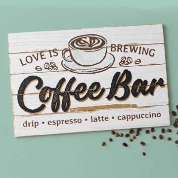 Show details for Love Is Brewing A decorative sign with a coffee cup illustration and text that reads, “Love is brewing Coffee Bar,” followed by “drip, espresso, latte, cappuccino” on a white wood background with coffee beans nearby.