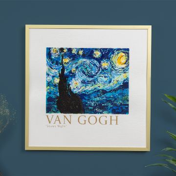 Show details for The Starry Night Framed print of Vincent van Gogh’s “Starry Night,” featuring swirling blue and yellow night sky above a dark cypress and village, with “VAN GOGH ‘Starry Night’” text below, hung on a dark blue wall.