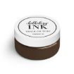 A small round jar of Chalk Couture Chalkology Ink with a white lid and brown contents. The label on the lid reads “chalkology INK, Chalk Couture, Permanent Ink.”.