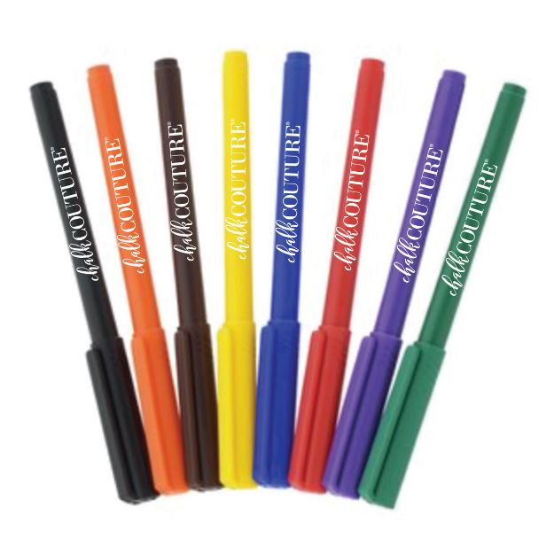Eight colored markers—black, orange, brown, yellow, blue, purple, red, and green—are standing upright in a row. Each marker has "chalk COUTURE" printed on its barrel in white lettering.