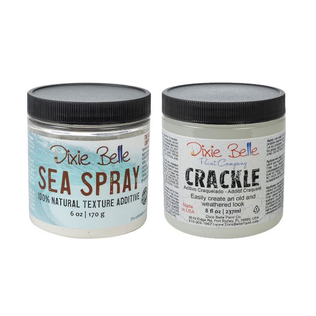 Two jars of Dixie Belle products: one labeled "Sea Spray 100% Natural Texture Additive" and the other labeled "Crackle" for creating an old and weathered look, both with black lids and white backgrounds.