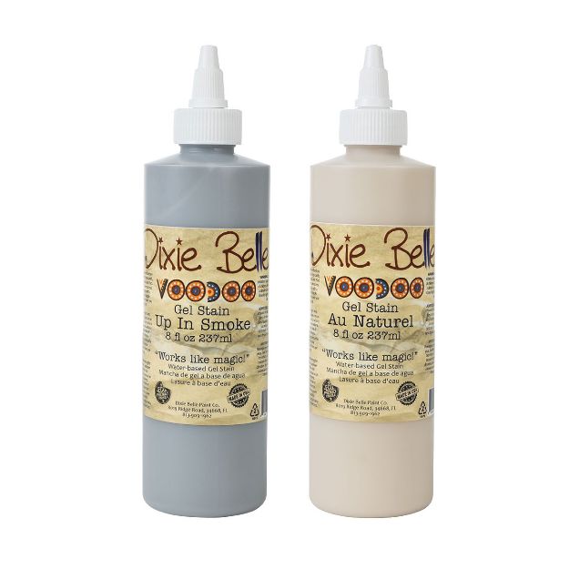 Two bottles of Dixie Belle Voodoo Gel Stain, one labeled "Up In Smoke" in gray and the other "Au Naturel" in beige, both with pointed caps and 8 fl oz (237 ml) labels.