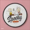 A round sign featuring cartoon characters Charlie Brown, Snoopy, and Linus sitting above the text "Spooky Crew Good Grief!" on a pink background.