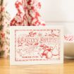 A white box labeled "Santa’s Sweets" with red vintage-style lettering and holiday illustrations sits on a wooden surface, with candy and festive fabric in the background.