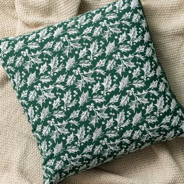 Show details for Square Pillow Cover (1-Pack, Forest, 17½" x 17½") A green square pillow with a white holly and berry pattern rests on a beige knitted blanket.