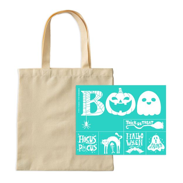 A plain beige tote bag next to a teal stencil sheet with white Halloween-themed designs, including “BOO,” a jack-o’-lantern, a ghost, “Trick or Treat,” “Hocus Pocus,” “Halloween,” and spider web motifs.