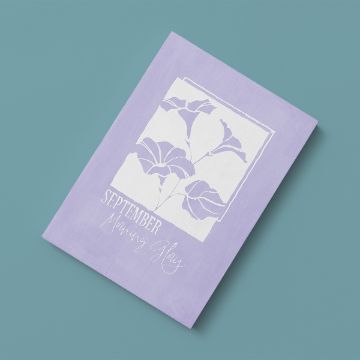 Show details for Morning Glory (September) A lavender notebook with a white illustration of morning glory flowers and the text "September Morning Glory" on the cover, placed on a teal surface.