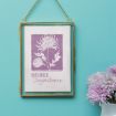 A framed artwork featuring a purple illustration of chrysanthemums labeled "November Chrysanthemum" hangs on a teal wall, with a vase of light purple chrysanthemums beside it.