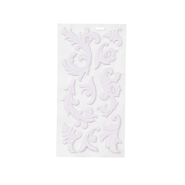 A white sheet displaying several ornate, decorative scrollwork embellishments with a floral and leaf design, arranged in various shapes and sizes.