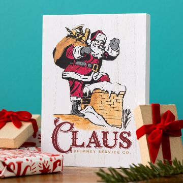 Show details for Claus Chimney Service Co. A festive card featuring Santa Claus carrying a sack and stepping into a chimney, with the text “Claus Chimney Service Co.” Below, there are wrapped gifts with red ribbons and spruce branches on a wooden surface.