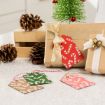 A wrapped gift with a gold ribbon sits on a counter next to pinecones, a small decorative tree, and festive gift tags with candy cane patterns in red, green, and brown.