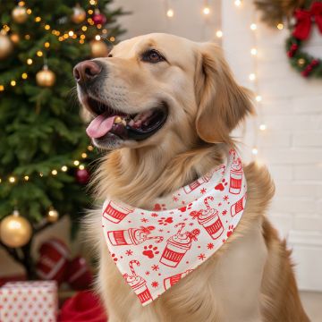 Show details for Pup Cup A golden retriever wearing a festive white bandana with red holiday designs sits indoors near a decorated Christmas tree and twinkling lights, looking happy with its tongue out.