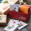 A red box labeled "Happy Holidays" holds festive cards and envelopes. Three cards with holiday-themed gnome illustrations are displayed on a wooden surface beside wrapped gifts with gnome designs.