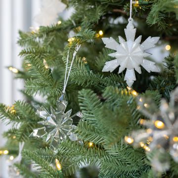 Show details for Snowflake Ornament Molds (4-Pack) Close-up of a Christmas tree decorated with white and clear snowflake ornaments and warm white string lights, with green pine needles in focus.