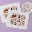 Two placemats with a whimsical North Pole map design showing houses, trees, and labeled landmarks, next to a white plate holding four star-shaped decorated cookies on a light purple surface.