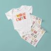 A white baby onesie with the words "SNOW CUTE" in colorful, patterned letters lies on a light blue surface next to two sticker sheets with similar patterned alphabet letters.