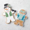 Two decorated cookies on a white surface: one is a snowman with a top hat, carrot nose, and buttons, holding sunglasses; the other is a gingerbread person wearing a blue vest, scarf, and sunglasses.