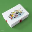 A white box with a red ribbon sits on a green surface. The lid features colorful illustrations of Peanuts characters, including Charlie Brown, Snoopy, and friends, gathered together and smiling.