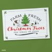 A sign with Snoopy and Woodstock by a Christmas tree reads: "Farm Fresh Christmas Trees. Pine, Spruce, Fir, Cedar." The background is white with holly decorations; the sign is set against a green surface.