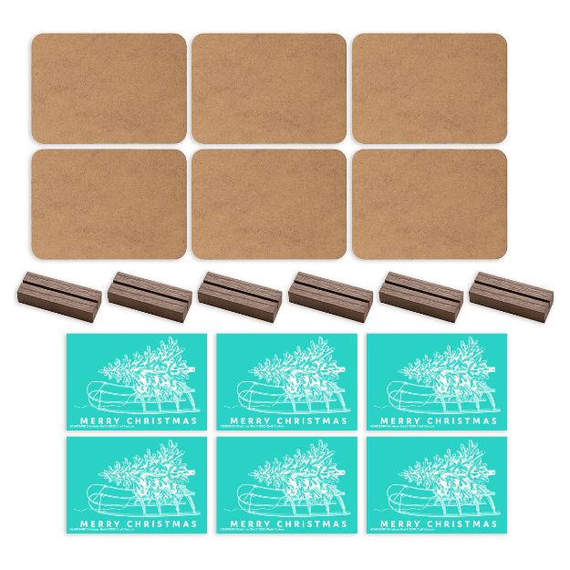Six blank brown cards, six small wooden holders, and six teal "Merry Christmas" cards with a white outline of a tree on a sled are arranged neatly on a white background.