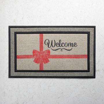 Show details for Debbie - Winter Welcome A rectangular doormat with a red ribbon and bow design, featuring the word "Welcome" in cursive script on a beige background with a black border.