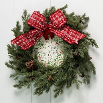 Show details for Debbie - Holiday Dove A green pine wreath with pinecones and a large red plaid bow hangs on a white wall. In the center is a sign that reads "Peace on Earth" with decorative foliage and berries around the text.