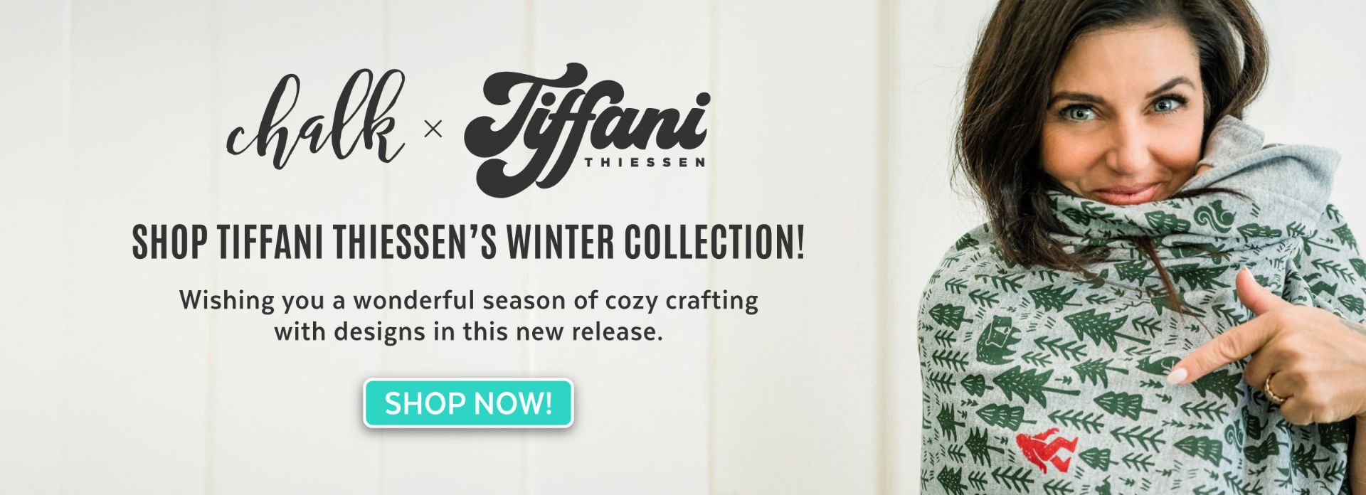 A woman with blue eyes, wrapped in a grey and green patterned blanket with a red heart, smiles and points at the blanket. Text promotes Tiffani Thiessen’s winter collection and a “Shop Now!” button is shown.