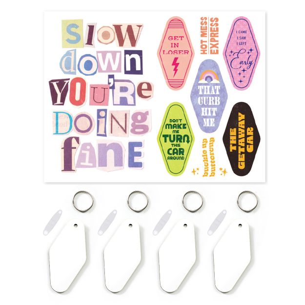 A sheet of colorful stickers with motivational and humorous phrases, plus three blank white keychains with metal rings and attached clear plastic name tags below the sheet.