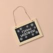 A small chalkboard sign with a wooden frame hangs on a string. It reads "flakes welcome" in white text, surrounded by white snowflake designs, on a light beige background.
