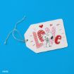 A white gift tag with "LOVE" in red letters and a drawing of Snoopy holding flowers, surrounded by hearts, on a bright blue background. A piece of twine is attached to the tag.